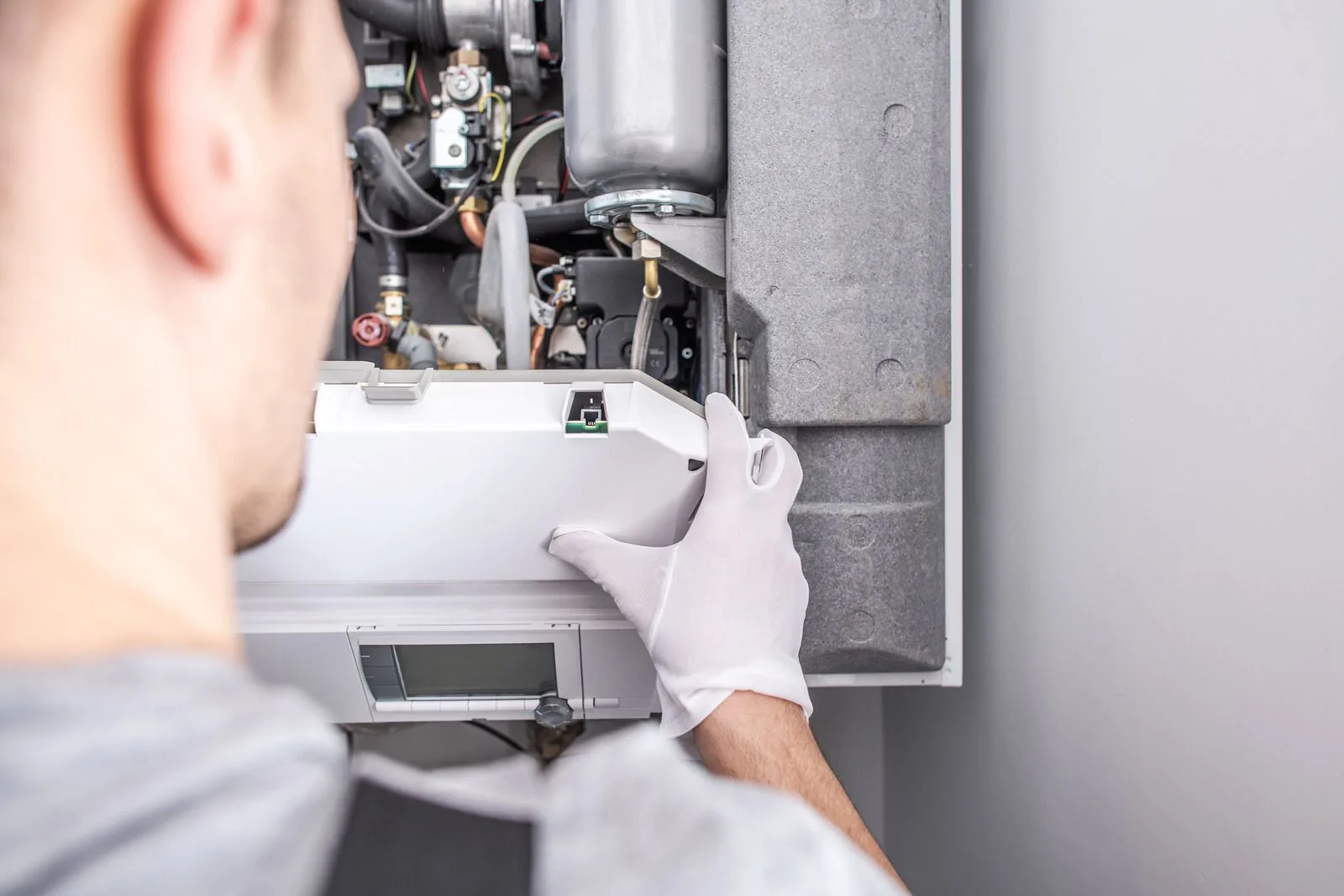 Technician repairing a water heater, wearing gloves and focused on internal components, emphasizing expertise in water