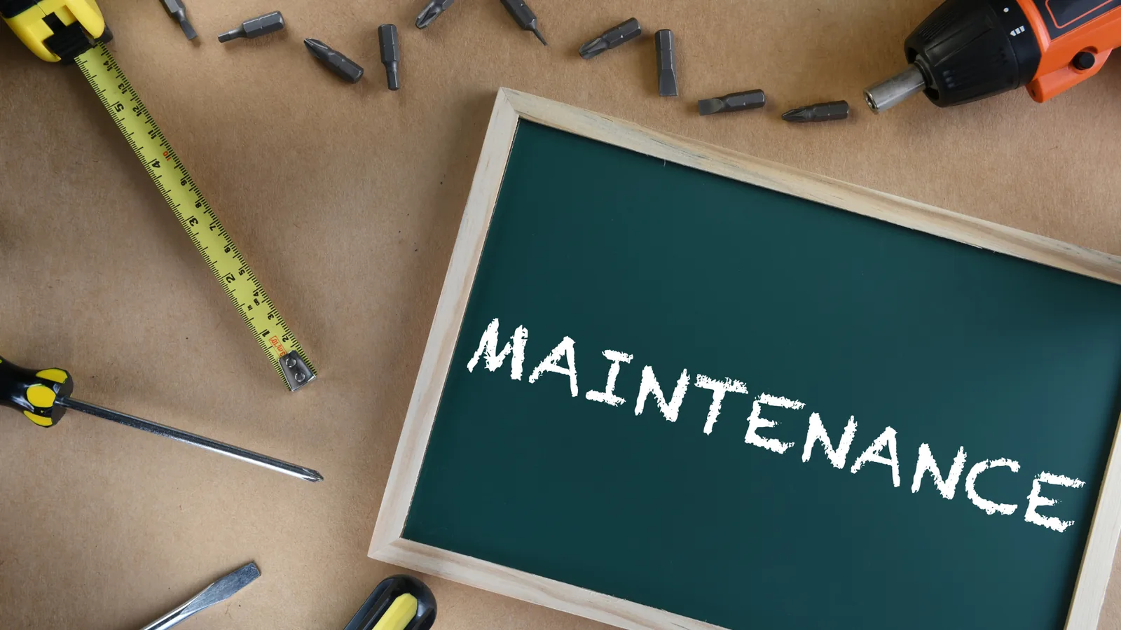 Chalkboard displaying the word "MAINTENANCE" surrounded by tools like a screwdriver, measuring tape, and drill