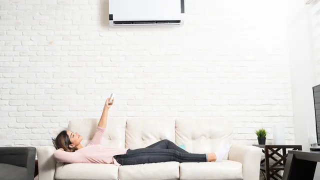 woman lying in the couch turning on the mini split AC unit