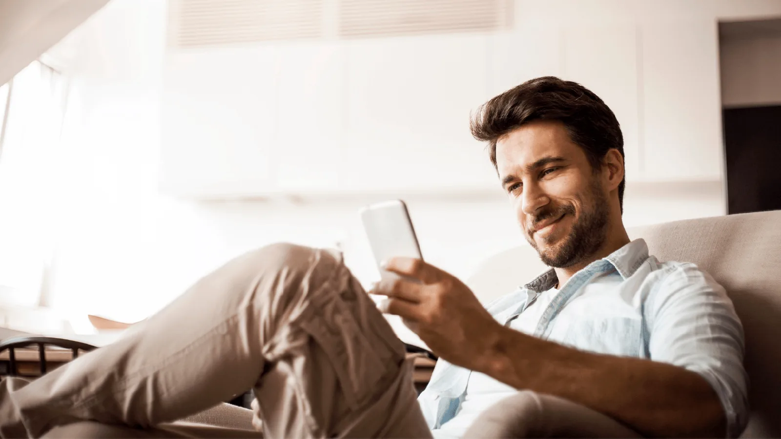 Man sitting comfortably in a chair using a smartphone, illustrating the convenience of contacting HVAC services for heater maintenance.