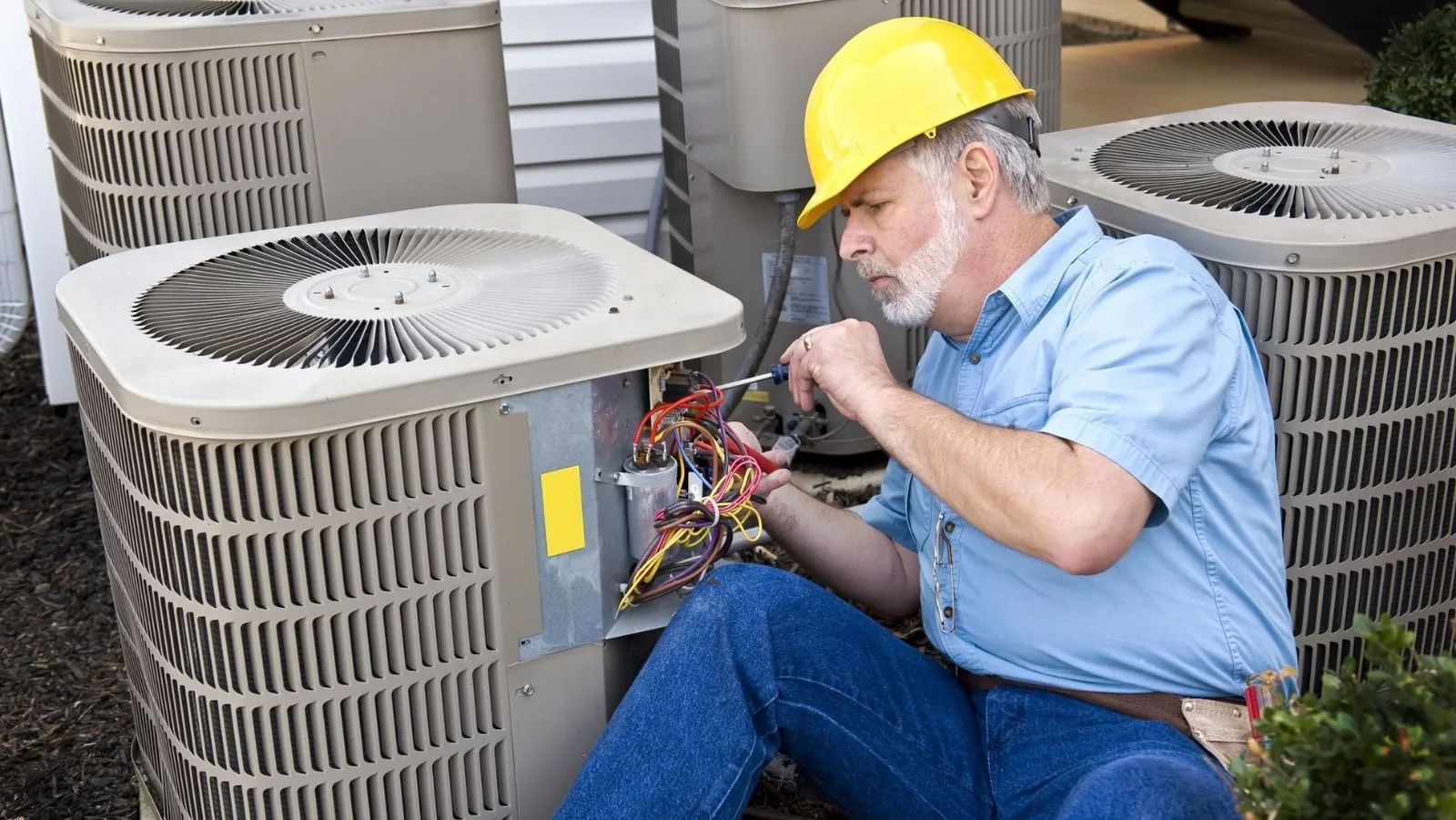 Technician repairing HVAC unit outdoors, showcasing commercial heating and cooling system maintenance.