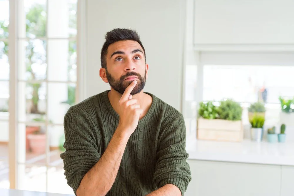 Man contemplating in a modern kitchen, considering options for dual fuel heating systems.