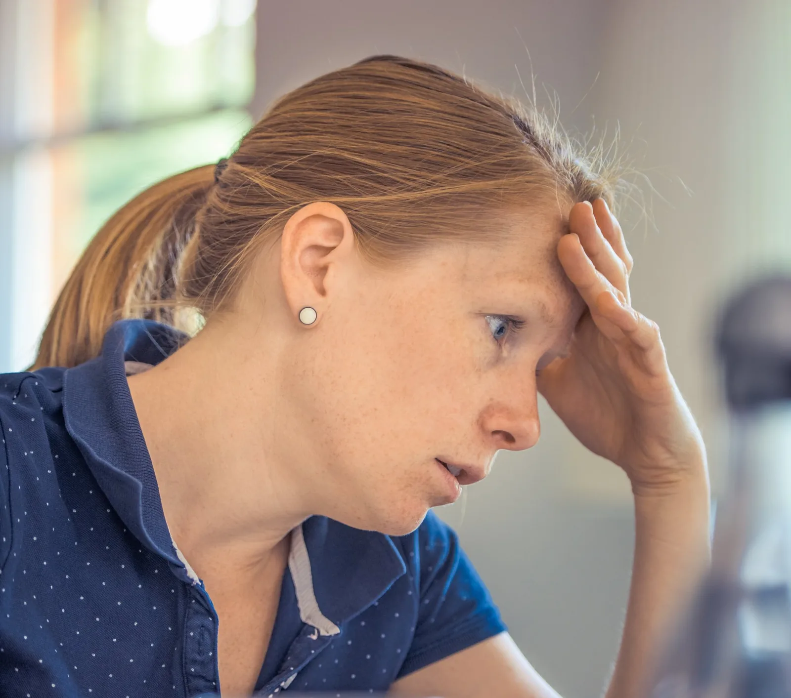 Woman with a worried expression, hand on forehead, indicating stress or concern, relevant to troubleshooting furnace issues.