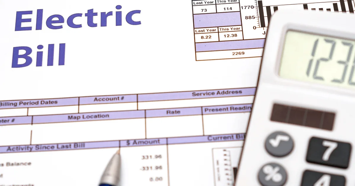 Electric bill document with highlighted title, calculator, and pen, illustrating energy costs related to HVAC usage and maintenance strategies.