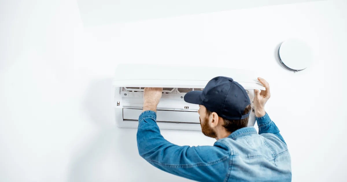 HVAC technician performing maintenance on a ductless heat pump, emphasizing the importance of annual service for optimal