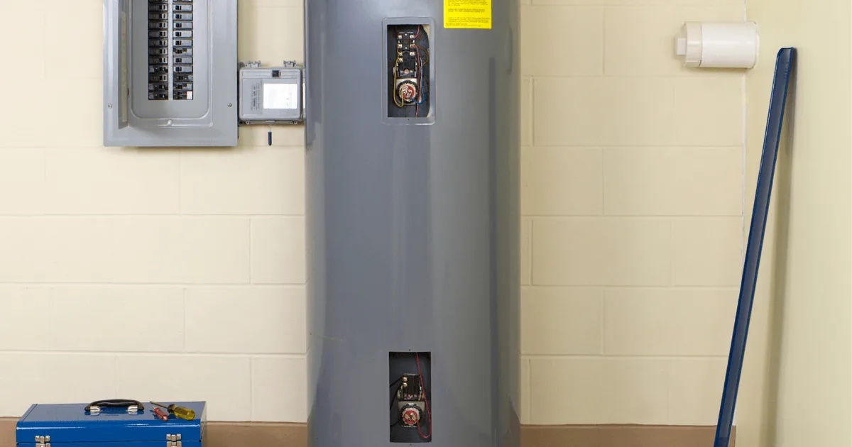 Heat pump water heater with visible electrical panel and tools, illustrating HVAC installation and maintenance services.