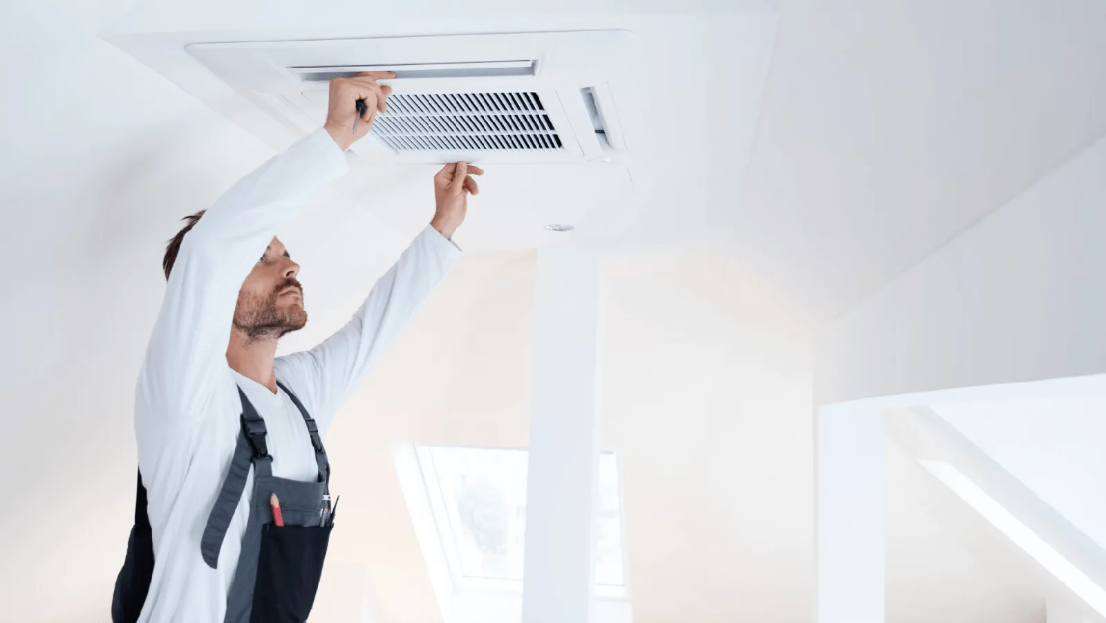 Technician performing maintenance on a ductless mini-split air conditioning unit in a home setting, emphasizing HVAC service and repair.