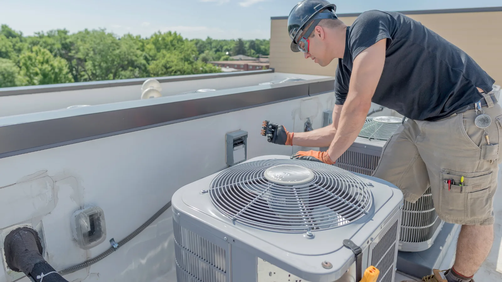 HVAC technician performing maintenance on rooftop air conditioning units, ensuring optimal performance and longevity