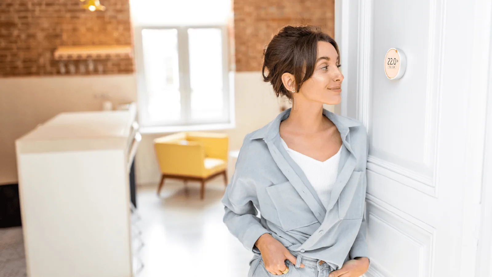 Woman adjusting a modern thermostat displaying 22°C in a stylish home setting, illustrating the importance of thermostats for HVAC energy efficiency.
