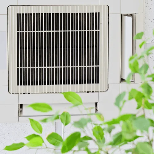 Ductless mini split air conditioning unit installed indoors, surrounded by green foliage, illustrating HVAC solutions
