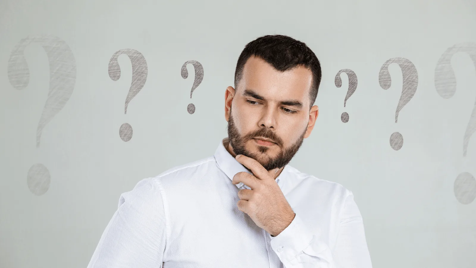 Man pondering with a thoughtful expression and question marks in the background, illustrating inquiries about ductless