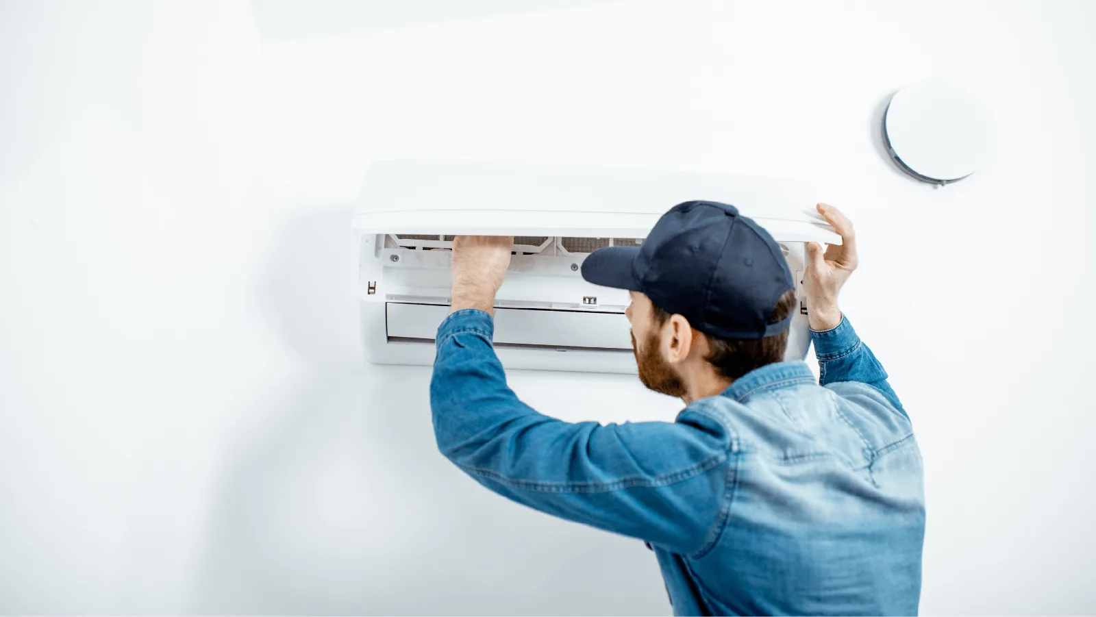 Technician performing maintenance on a ductless mini-split air conditioning unit, emphasizing HVAC service and efficiency.