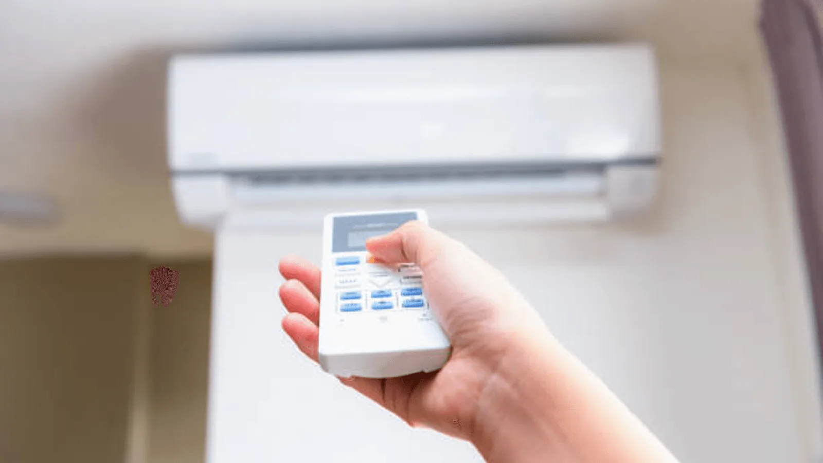 Hand holding remote control for ductless mini-split air conditioning unit, emphasizing HVAC settings for comfort and energy efficiency.
