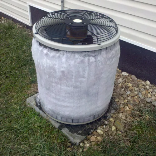 Frozen outdoor HVAC unit covered in ice, illustrating common HVAC issues related to freezing, relevant to HVAC maintenance and repair services.