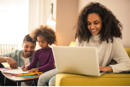 Family engaged in home activities, woman using laptop for work or research, child drawing
