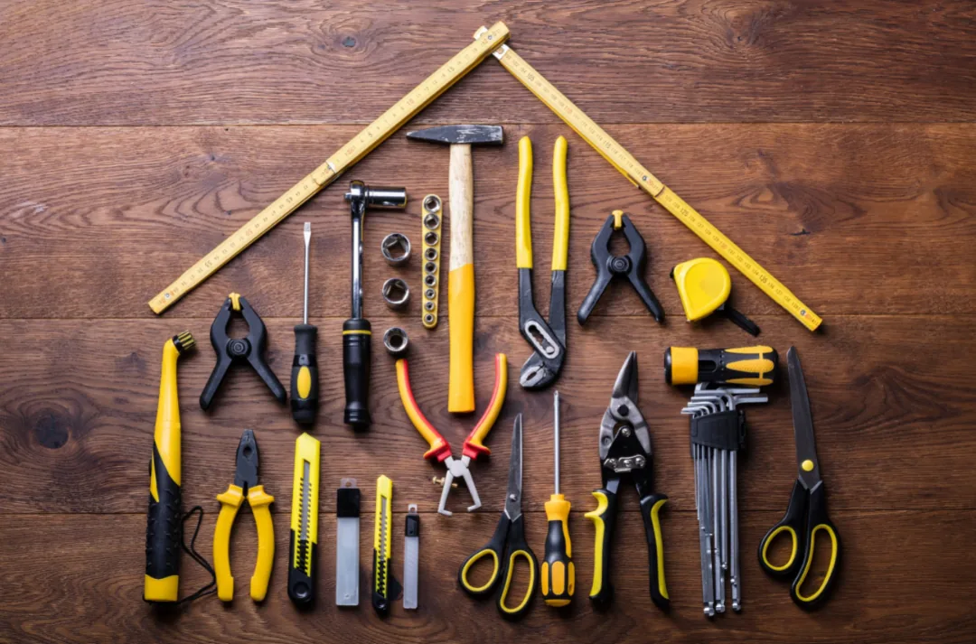 Tools arranged in a house shape on wooden background