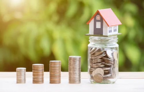 Model house atop a jar filled with coins, representing home equity growth through HVAC upgrades and investments in home improvement.