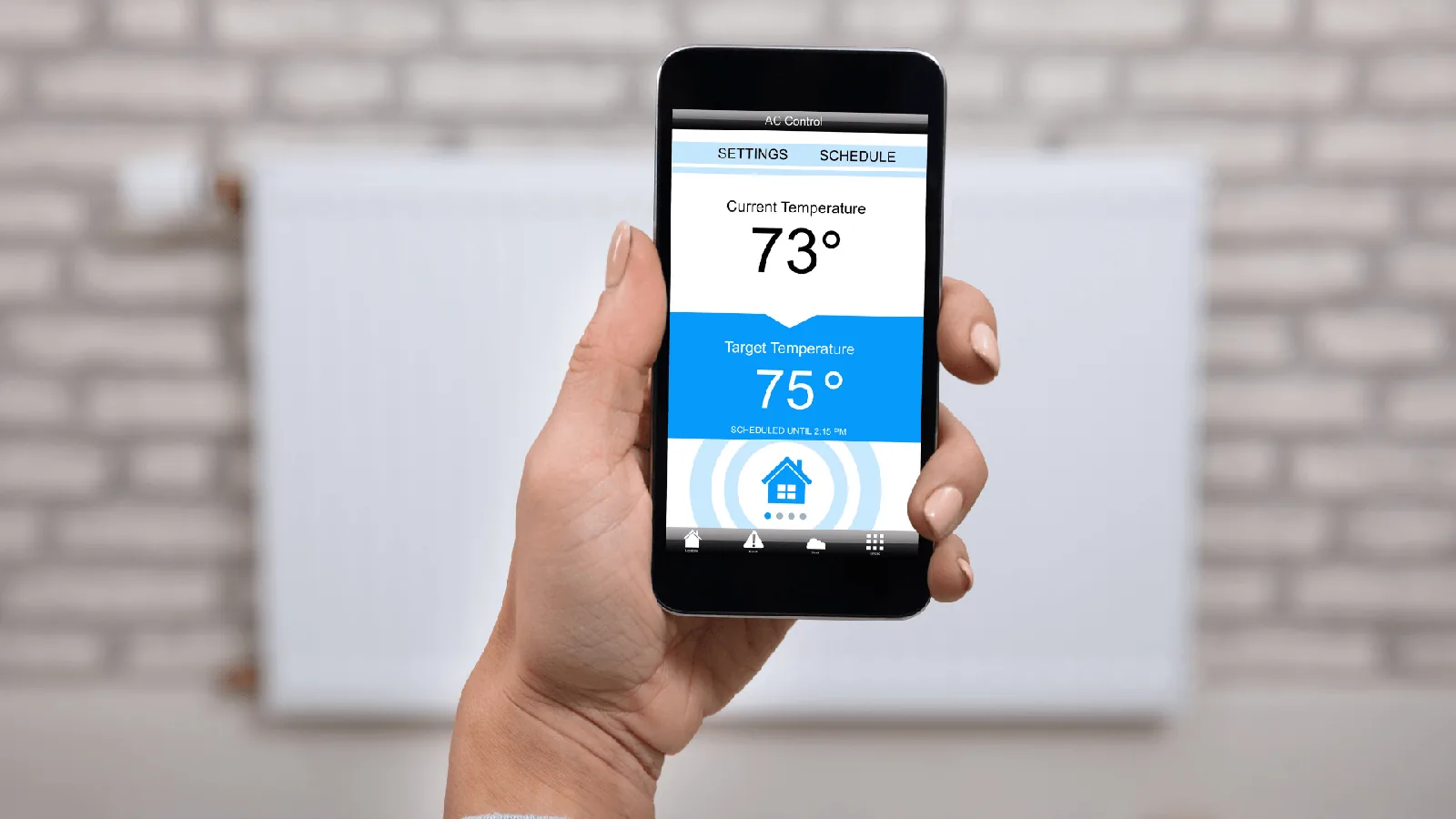 Person holding smartphone displaying HVAC control settings, showing current temperature of 73°F and target temperature