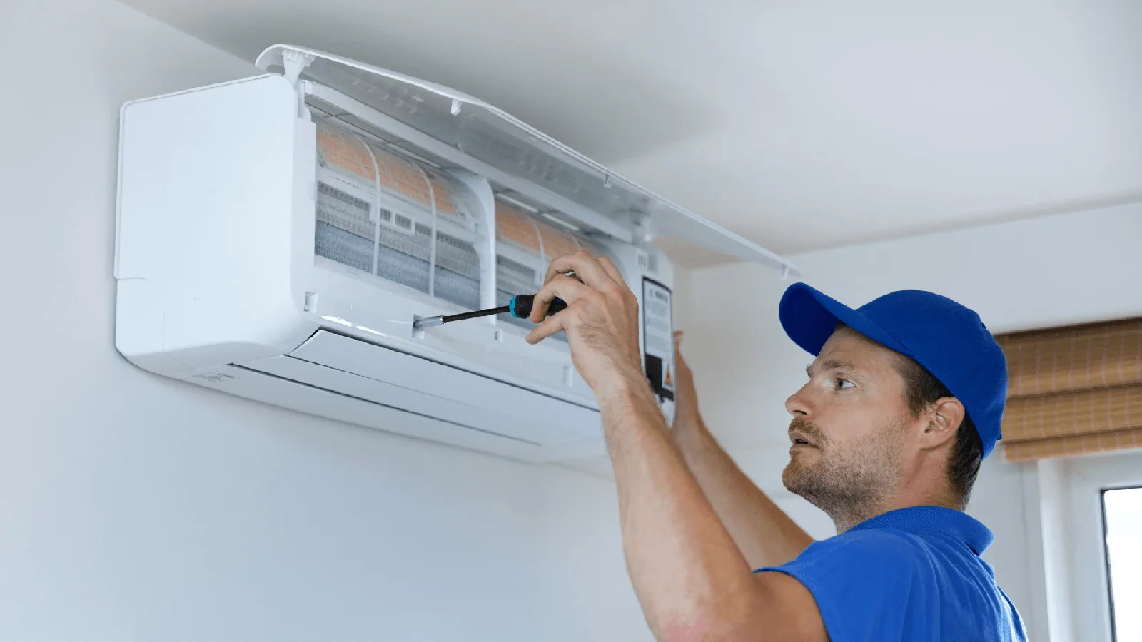 HVAC technician performing maintenance on a wall-mounted air conditioning unit, emphasizing service quality and technical expertise.