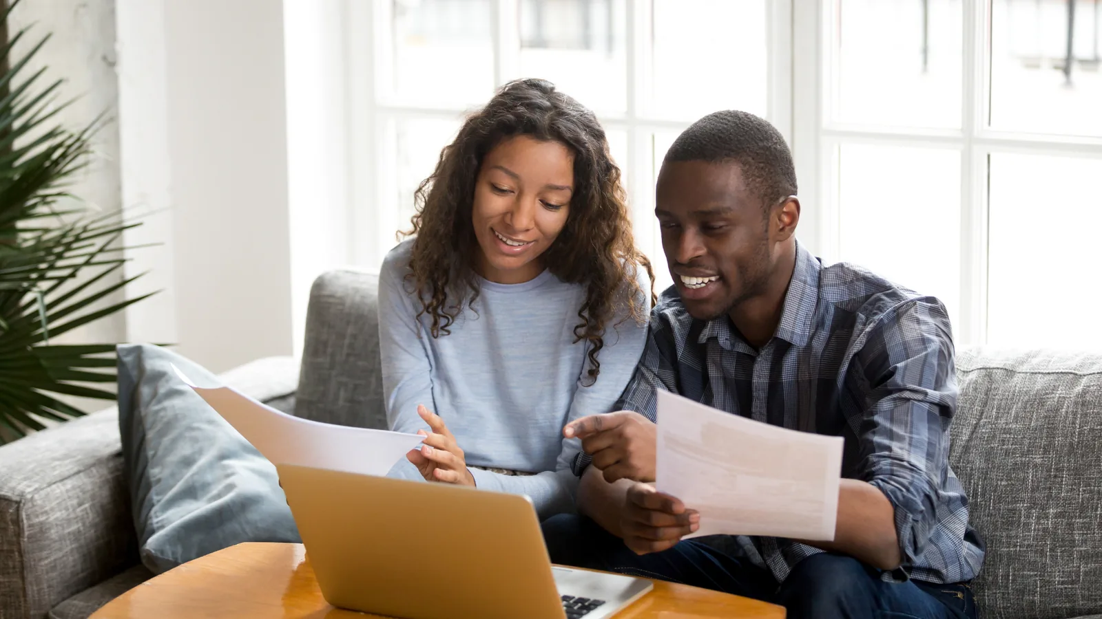 Couple reviewing HVAC quotes on laptop while discussing options for installation and maintenance services.