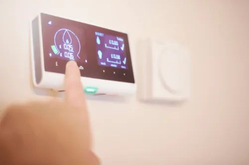Smart thermostat being adjusted, displaying energy usage metrics and settings, illustrating remote access and