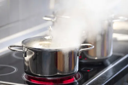 Steam rising from a pot on a stovetop, illustrating a common indoor heat source that can affect HVAC efficiency.