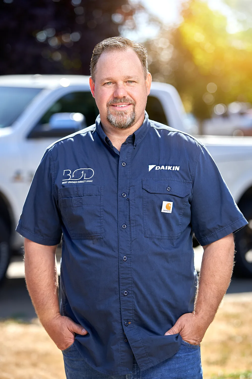 Best Owner Direct HVAC & Electrical team member in a company shirt in front of a service truck