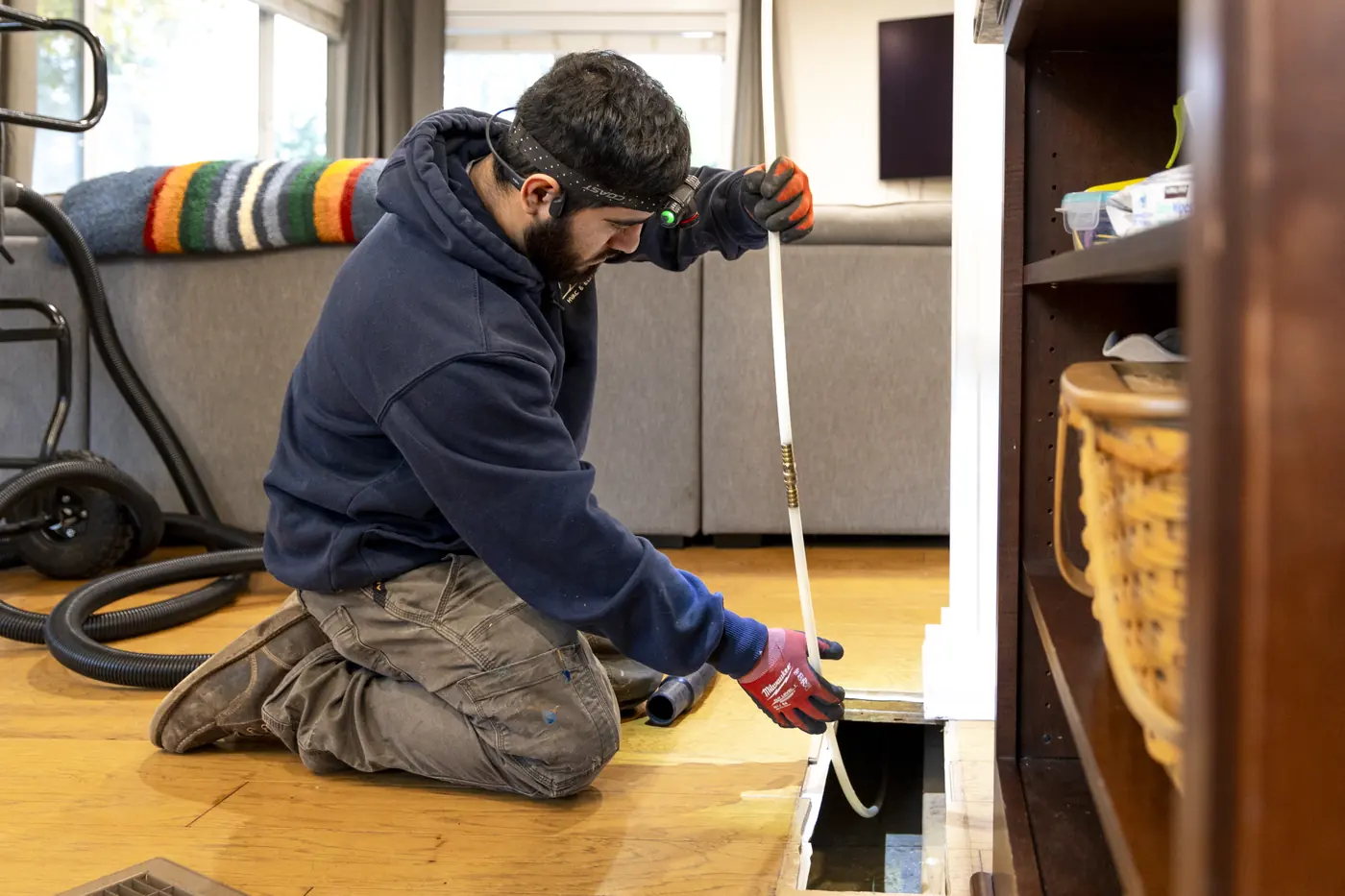 Technician cleaning a floor register duct with a whip line
