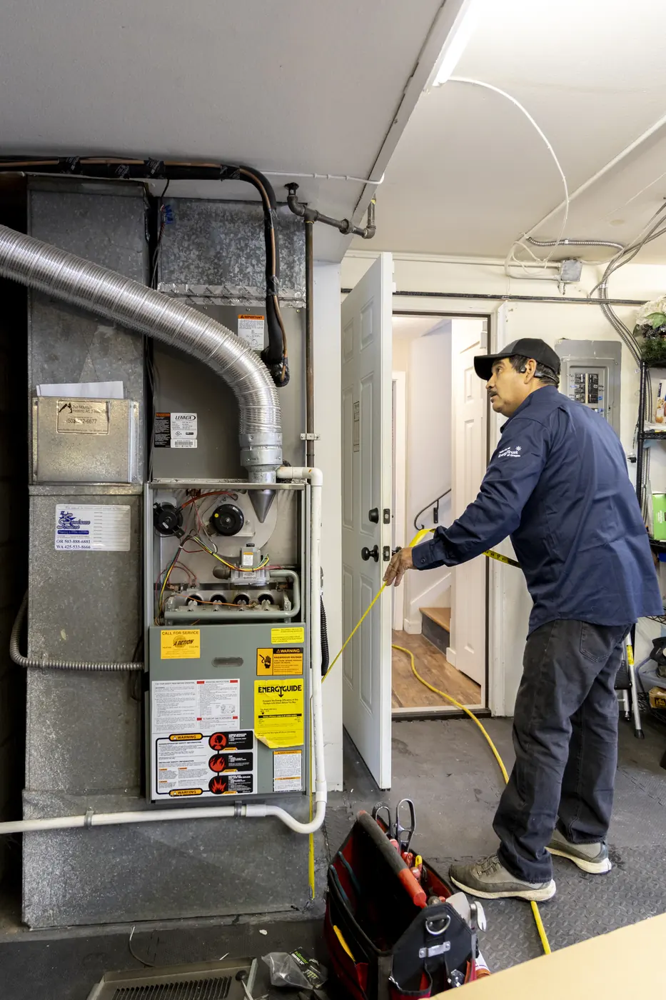 Technician inspecting a gas furnace in a garage mechanical room