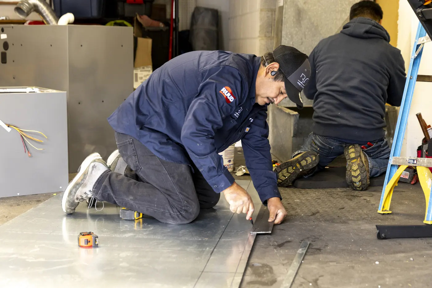 Two technicians laying out sheet metal on the shop floor