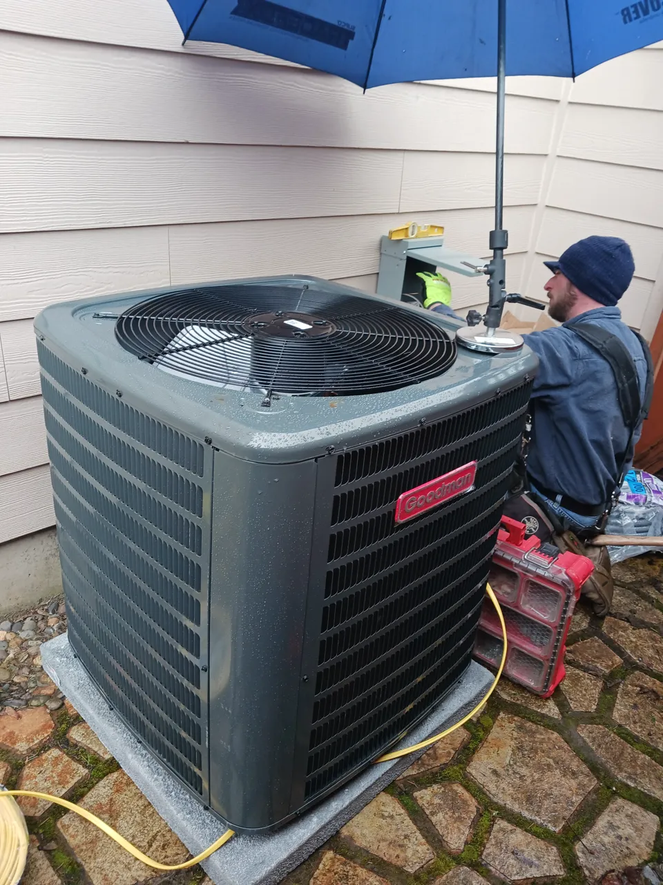 Technician Josh servicing an outdoor Goodman AC condenser in the rain